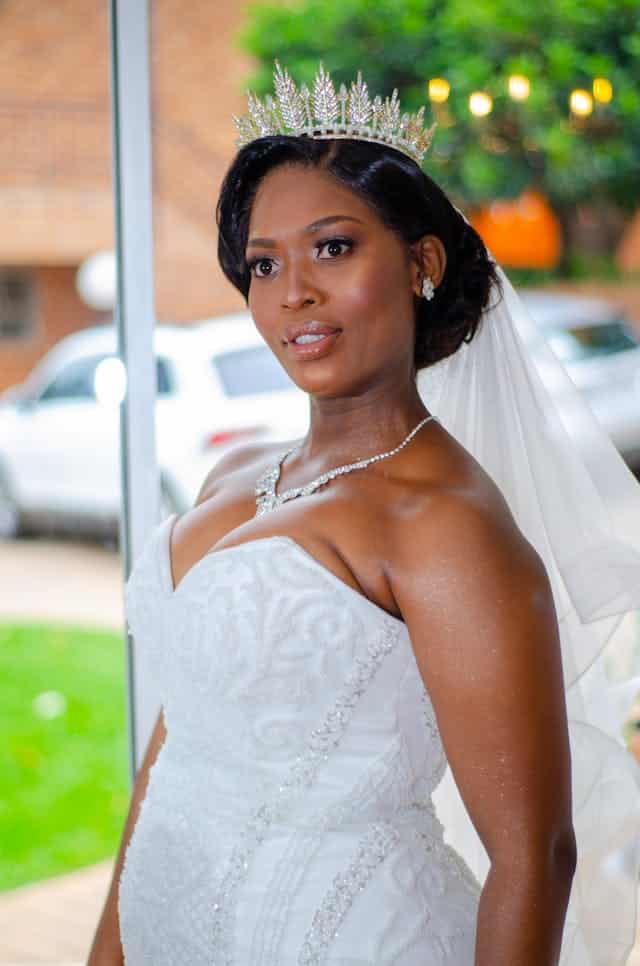Black bride in wedding dress standing on street and looking away